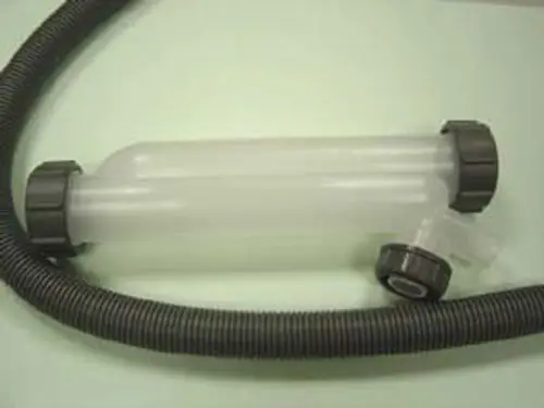 Transparenter Siphon mit zwei Anschlussstellen und flexibler, schwarzer Schlauchleitung. Teil eines Heizsystems von Remeha.